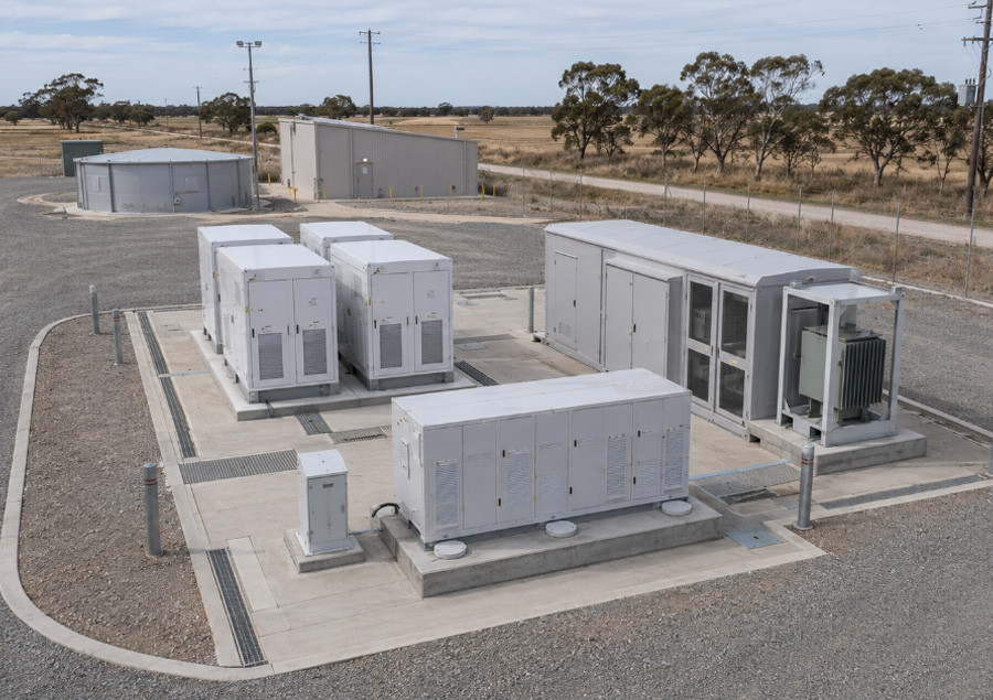 Close view of battery and inverter units on concrete pads at a rural site