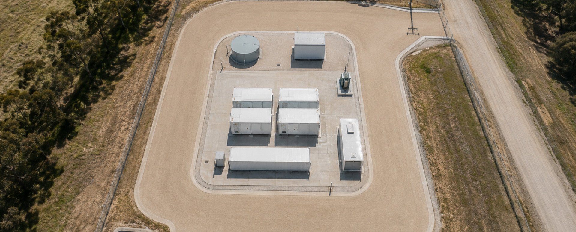Aerial view of a fenced community battery site next to a rural road