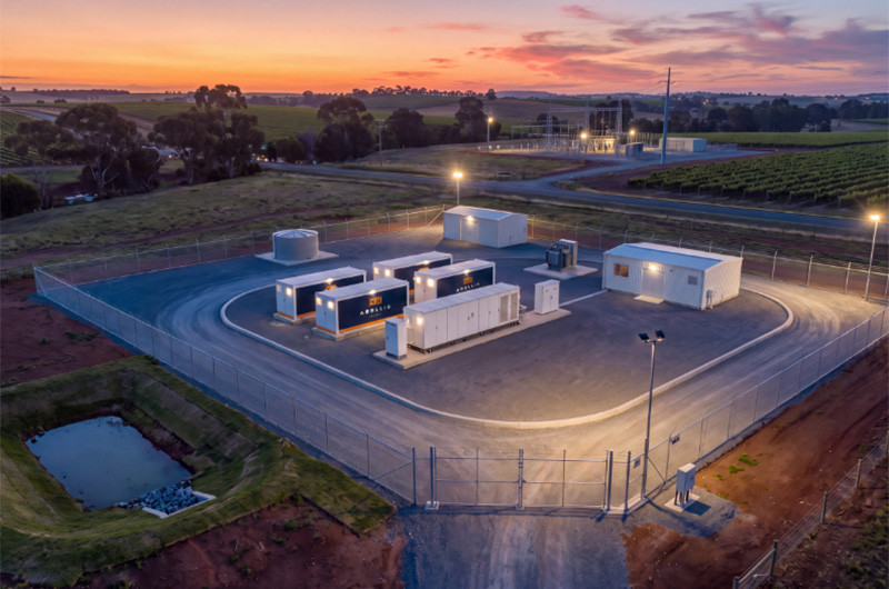 Battery compound with Arellis-branded units, lit at dusk among vineyards
