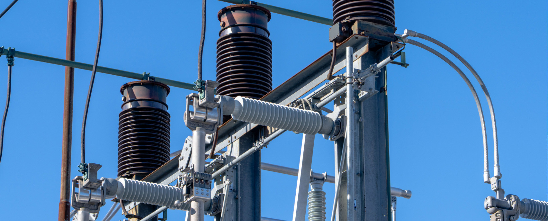 Close-up of high-voltage substation equipment against a blue sky